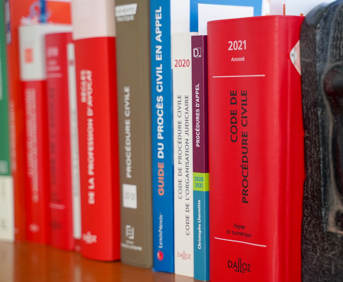Étagère du cabinet : codes Dalloz rouges, Guide du procès civil en appel et l'ouvrage « Procédures d'appel » de Christophe Lhermitte