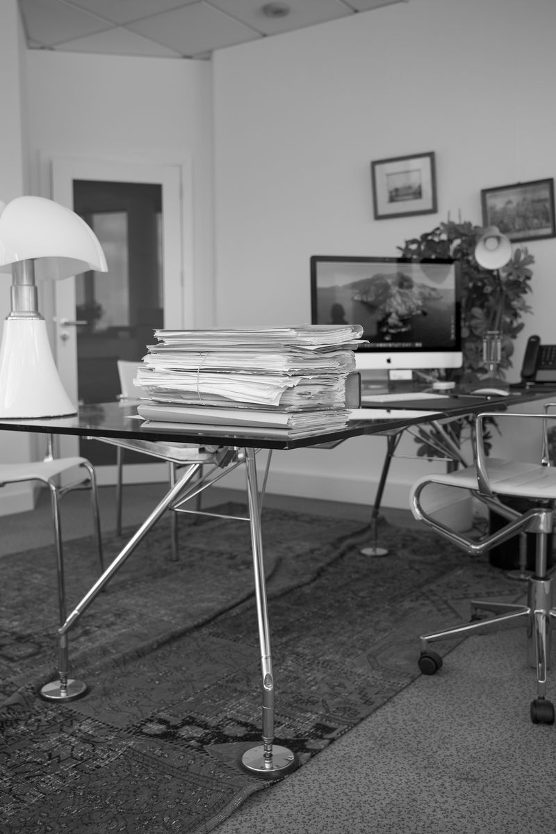 Bureau du cabinet en noir et blanc, piles de dossiers sur une table de verre