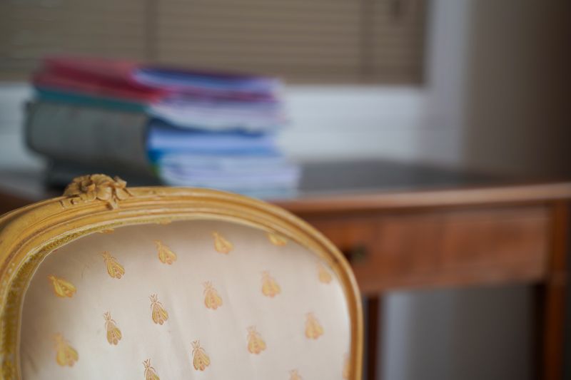 Fauteuil doré du cabinet devant un bureau ancien et une pile de dossiers